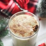 vegan eggnog in a glass with a cinnamon stick in it