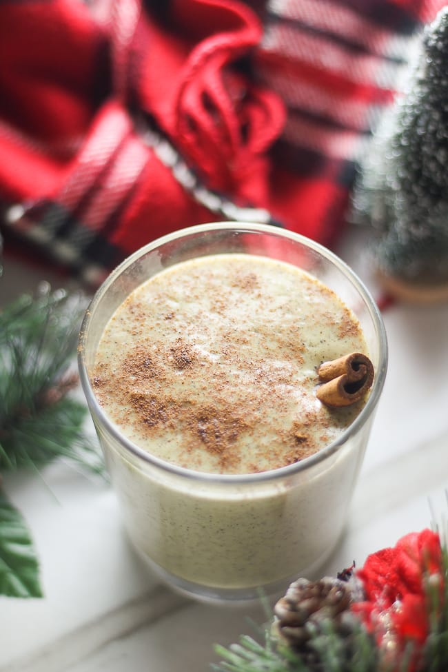 vegan eggnog in a glass with a cinnamon stick in it 