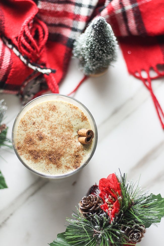 top angle of vegan eggnog in a glass with a cinnamon stick in it 