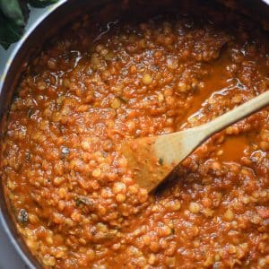 lentil tomato sauce in a pot with wooden ladle
