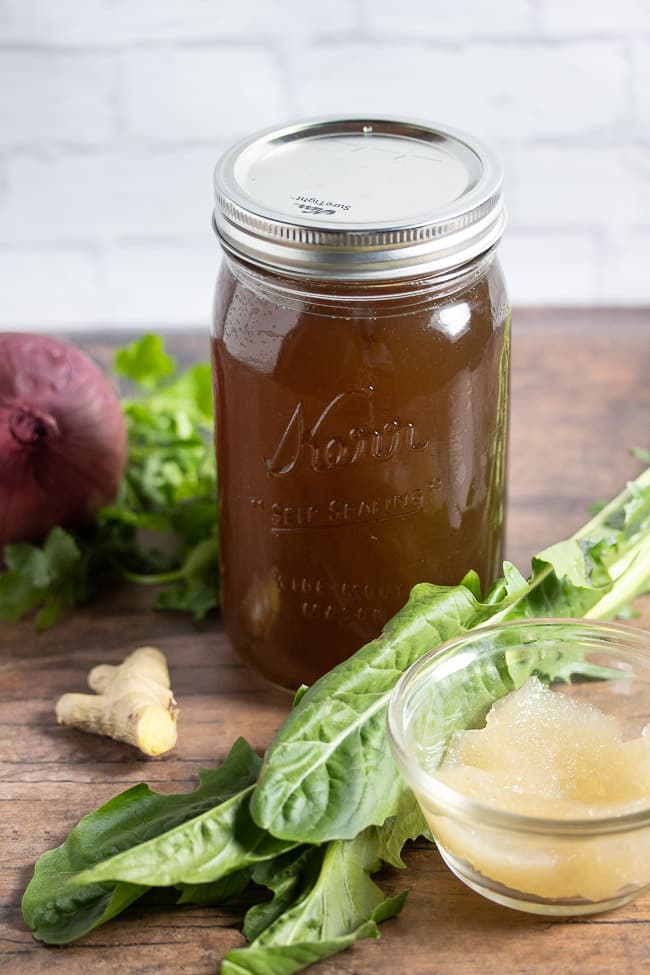 top angle vegan broth in a mason jar on a table with vegetables and sea moss gel