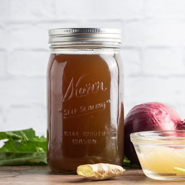 vegan broth in a mason jar on a table with vegetables and sea moss gel