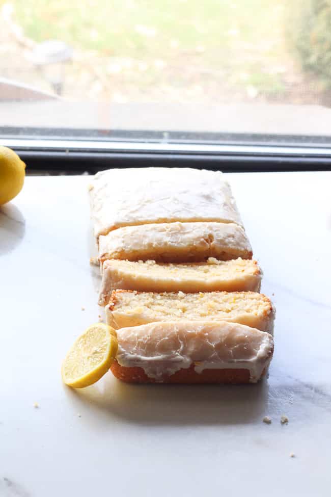 picture of lemon cake cut in slices by the window with a slice lemon next to it