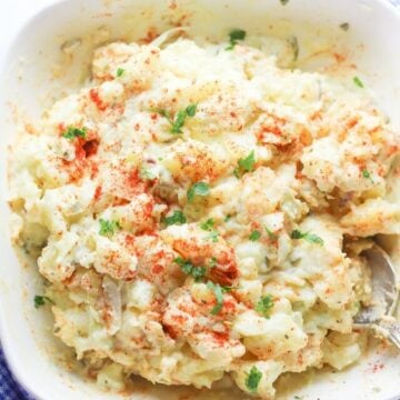 a picture of potato salad with paprika on top in on a white plate with a spoon