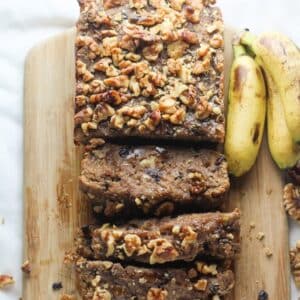 vegan banana bread on a cutting board next to baby bananas