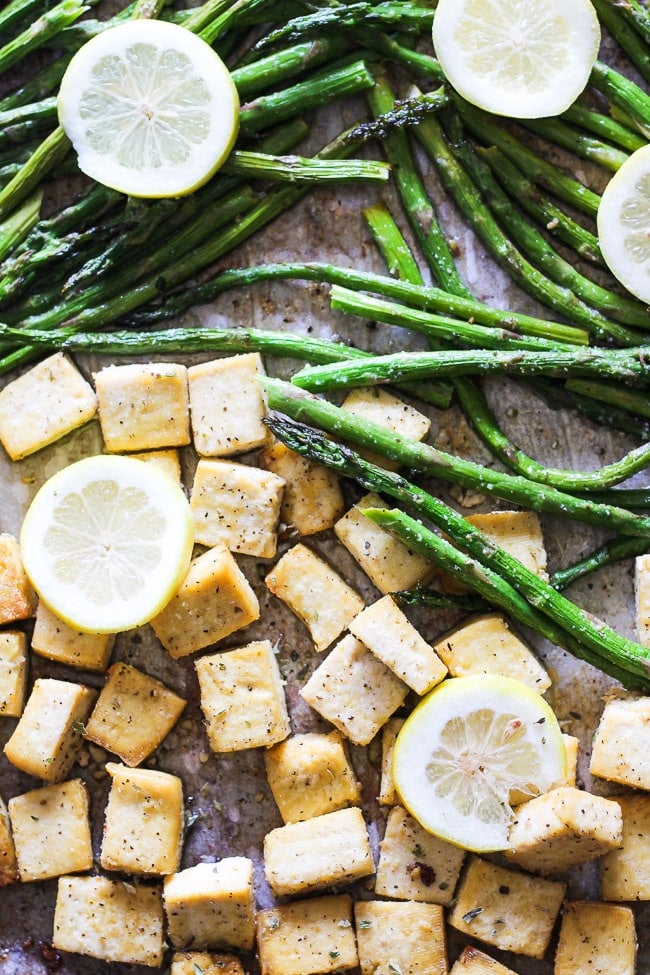 a picture of baked tofu and asparagus on a sheet pan with slice lemons