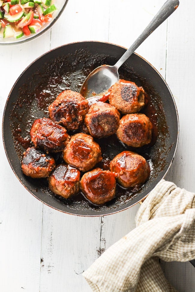 top angle bbq lentil meatballs in a skillet with a spoon