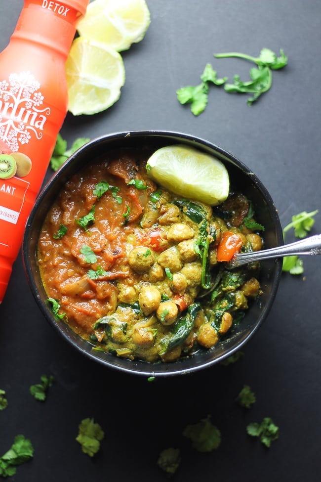 vegan chickpea curry and tomato soup in a black bowl with Karuna Beverage Bottle