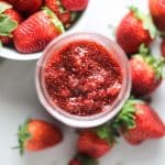 strawberry jam in a mason jar with fresh strawberries around it