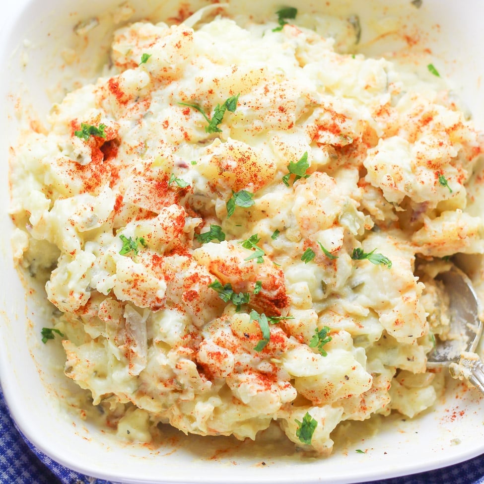 a picture of potato salad with red paprika sprinkled on top on a white plate