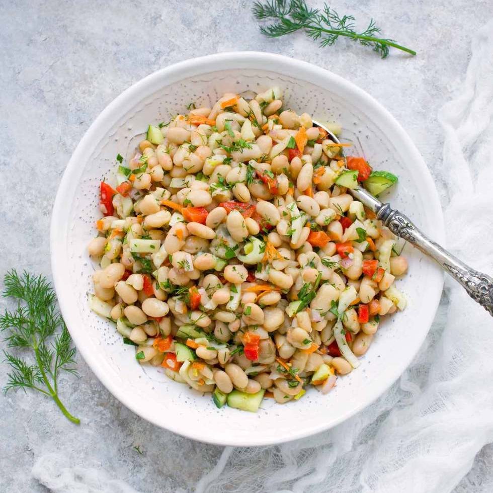 white bean salad on a white plate with a spoon