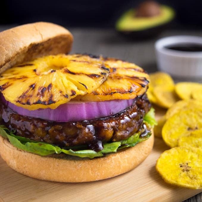vegan huli-huli vegan burger topped with grilled pineapple ring and onion on a bun