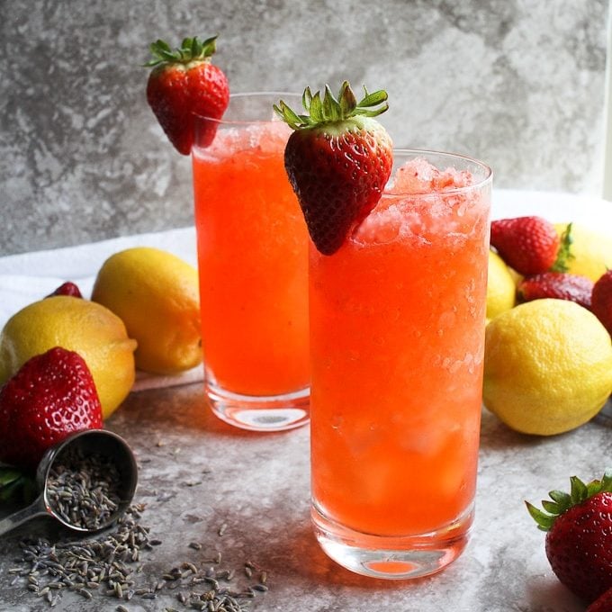 strawberry lemonade in 2 glasses with fresh strawberries and dried lavendar