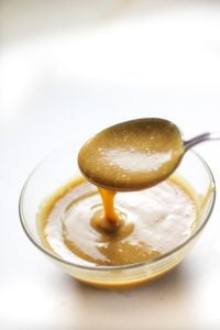 date caramel sauce dripping from a spoon into a bowl