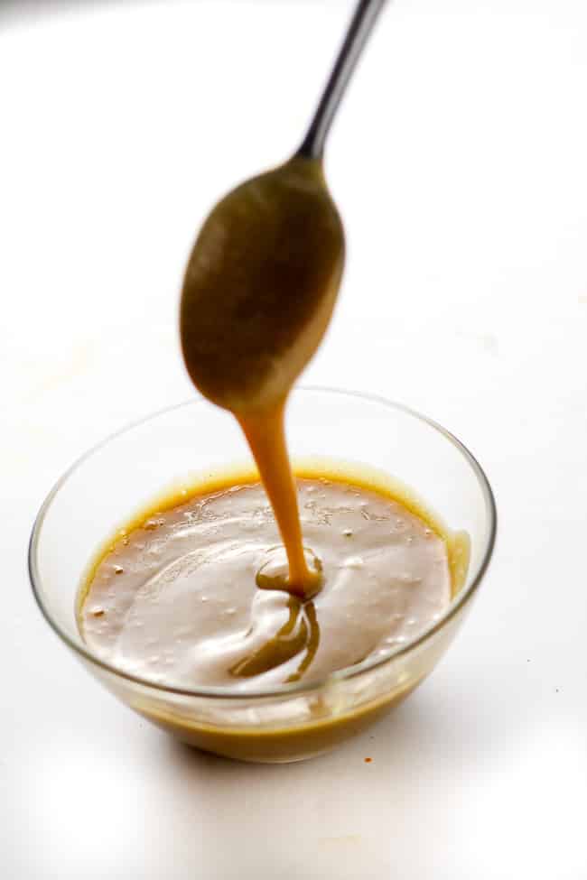 vegan caramel sauce dripping from a spoon into a bowl
