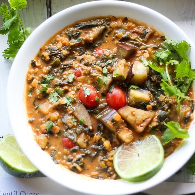 red lentil curry in a white bowl with lime slice and cilantro