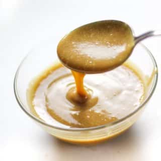 caramel sauce dripping from a spoon into a bowl