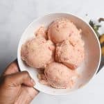 holding a bowl of strawberry banana ice cream in a white bowl