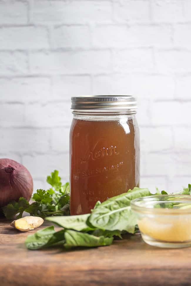 vegan broth in a mason jar on a table with vegetables and sea moss gel