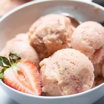 strawberry banana ice cream in a white bowl with a strawberry slice