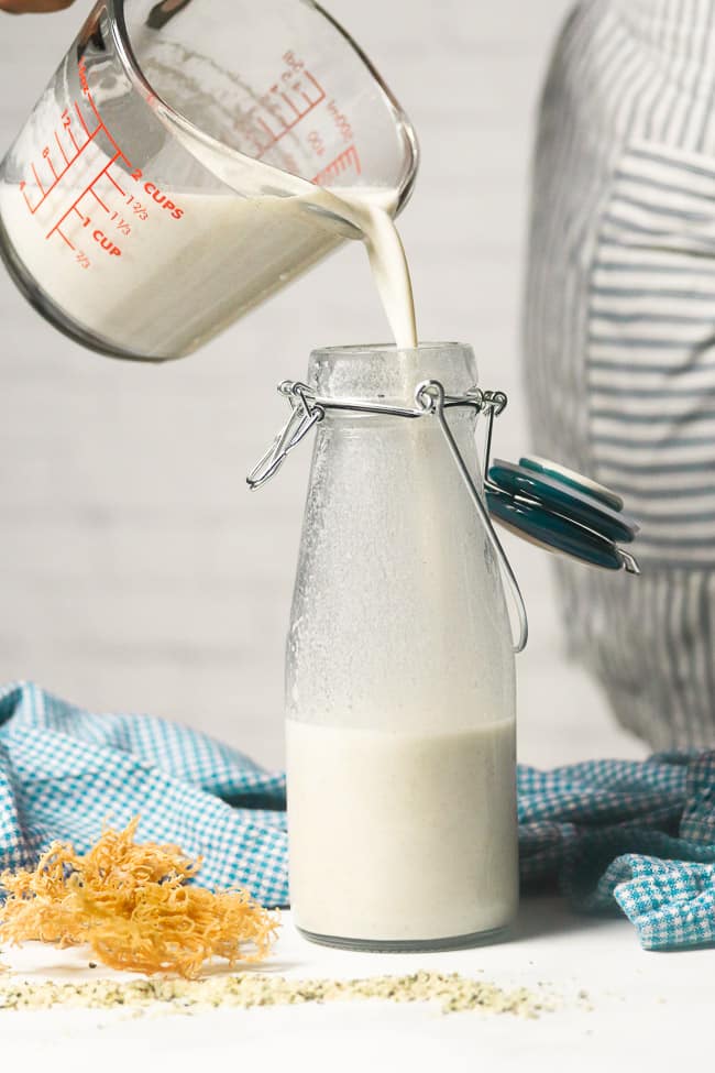 sea moss milk being poured into a glass milk bottle