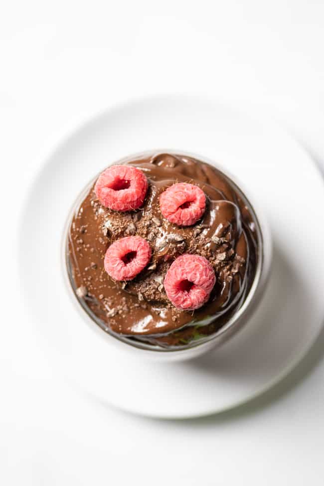 top view of vegan chocolate pudding in a glass topped with raspberries
