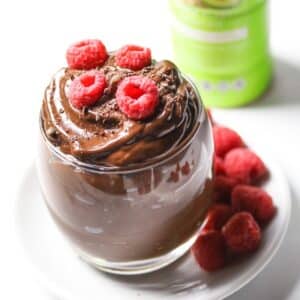 vegan chocolate pudding in a glass topped with raspberries
