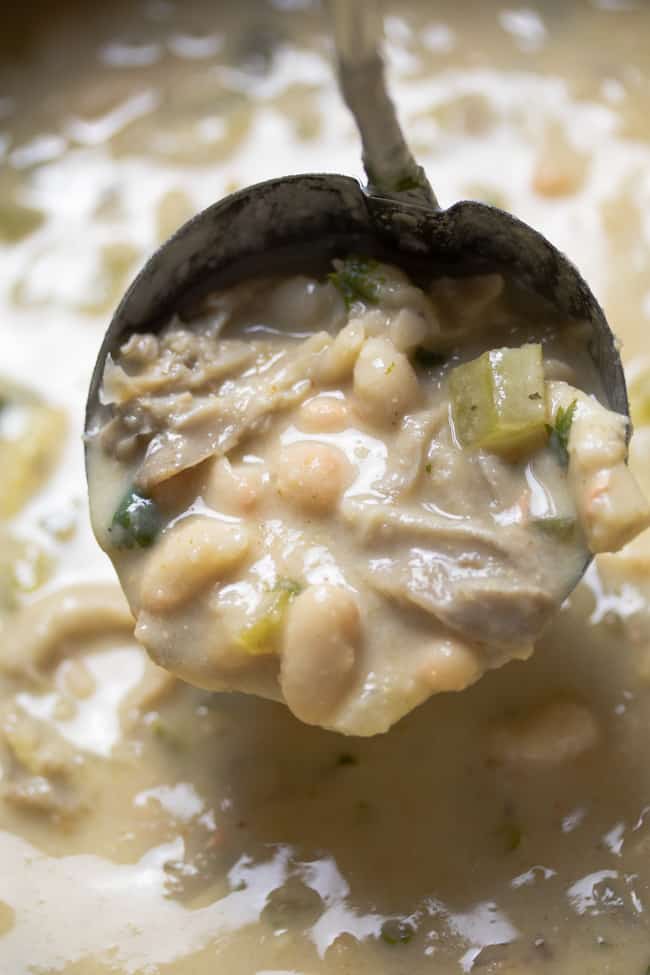 close up shot of white chili in a pot scooped up with a ladle