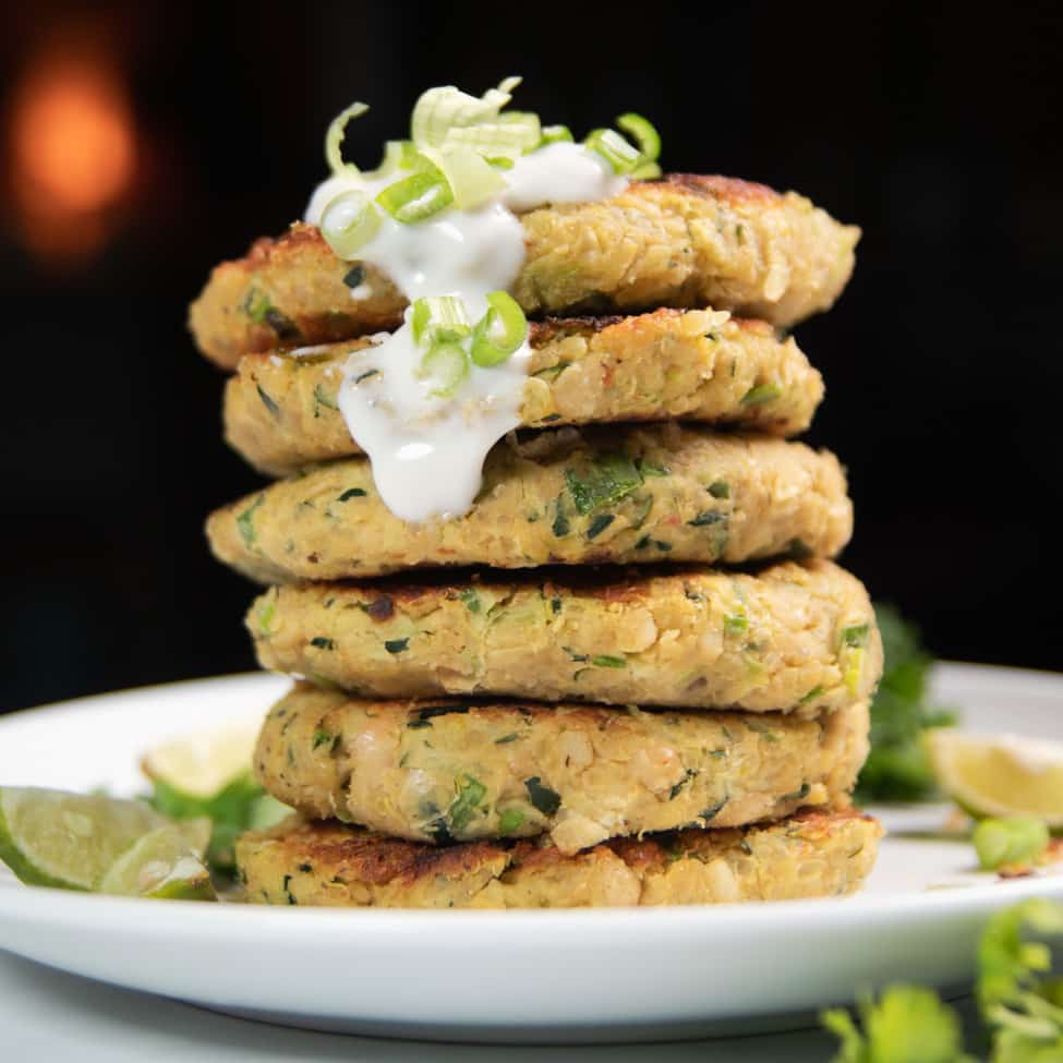 zucchini fritters stacked on top of each other topped with yogurt and green onions