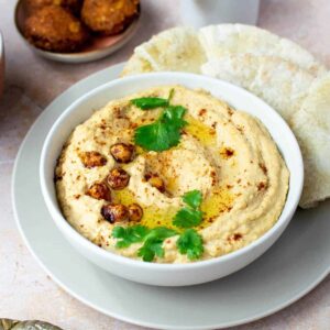 hummus in a white bowl topped with chickpeas and cilantro