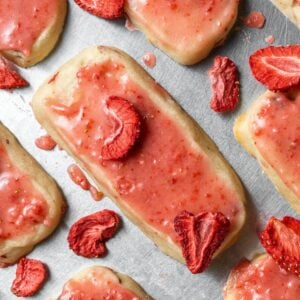 strawberry shortbread cookie on a sheet pan topped with strawberry sauce and dried strawberries