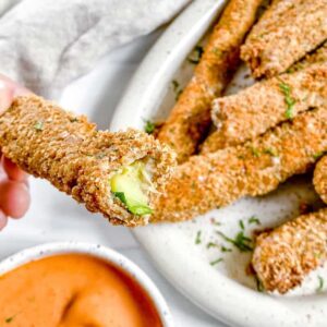 baked zucchini fries bitten into next to dipping sauce