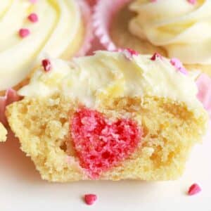 vanilla cupcakes with a pink heart shape inside of it