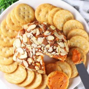 vegan cheese ball on a white plate with crackers