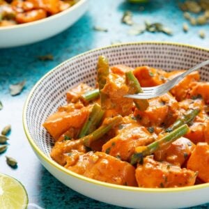 sweet potato curry in a white bowl with green beans on a fork