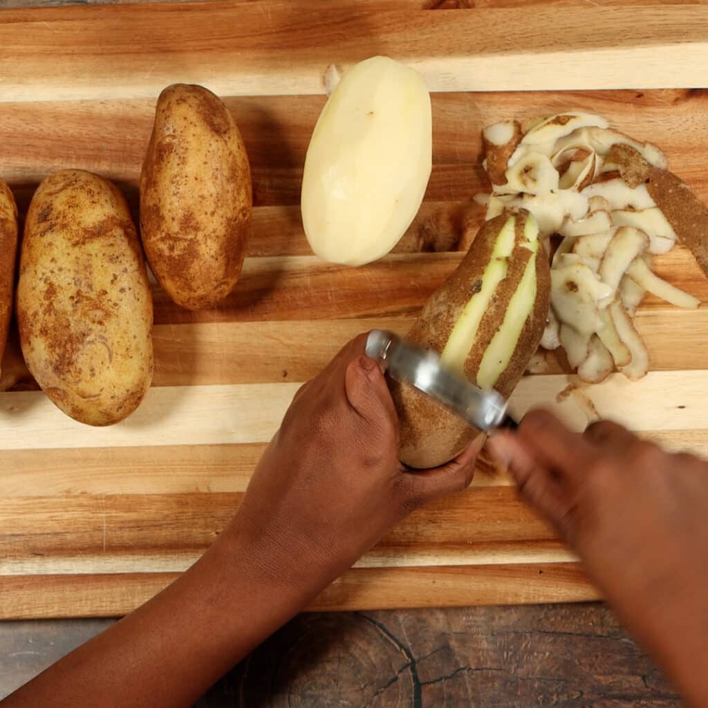 potatoes being peeled on a cutting board
