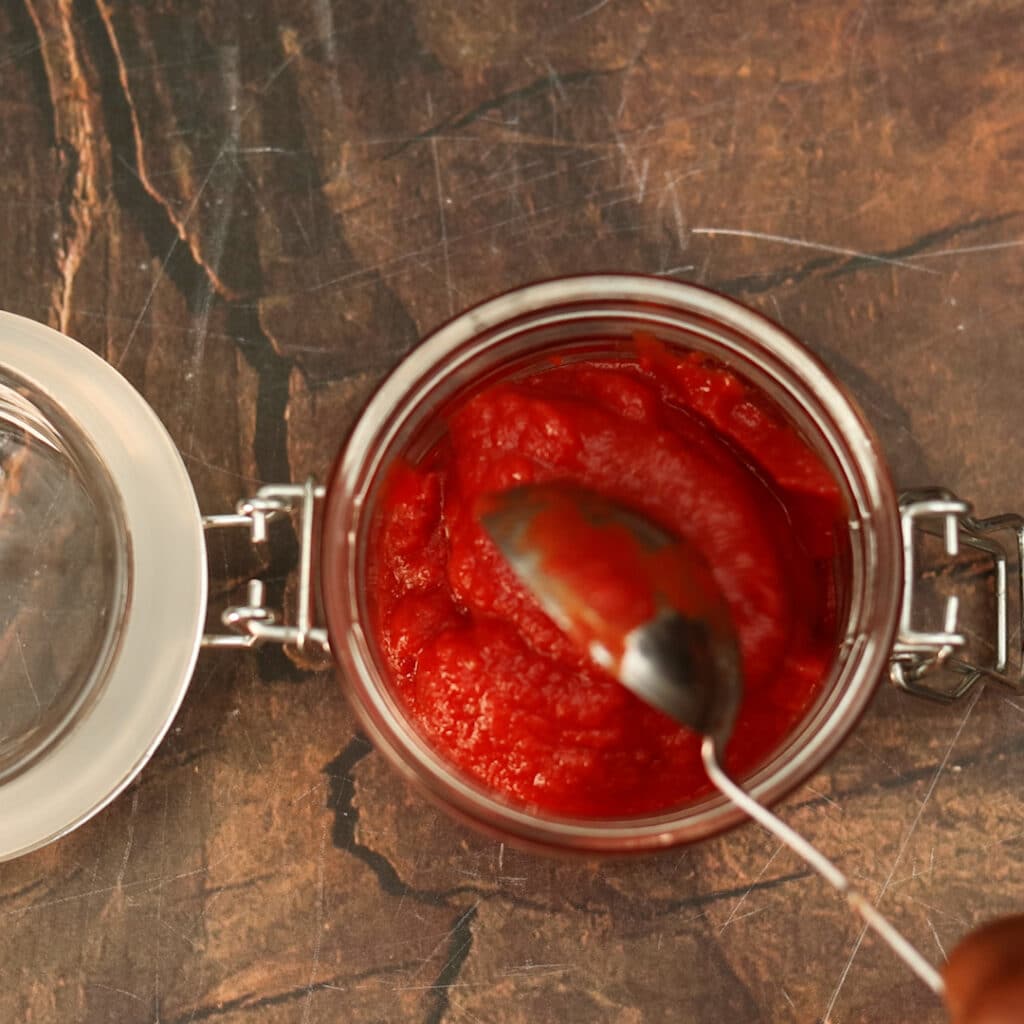 tomato paste added to a jar