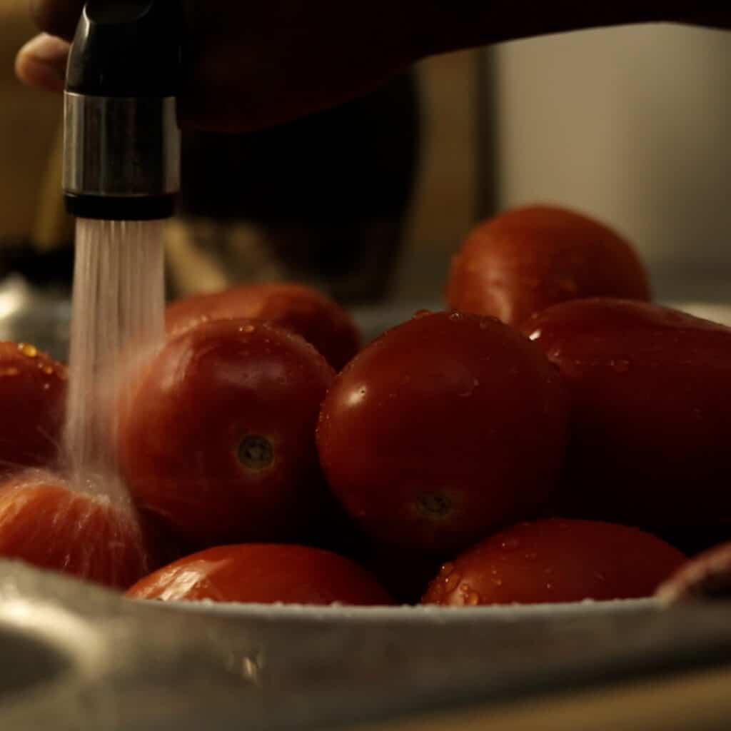 rinsing tomatoes in a sink