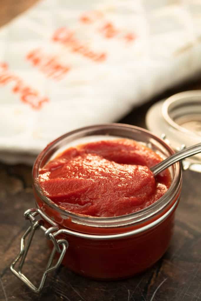 tomato paste in a glass jar with a spoon dipped into it
