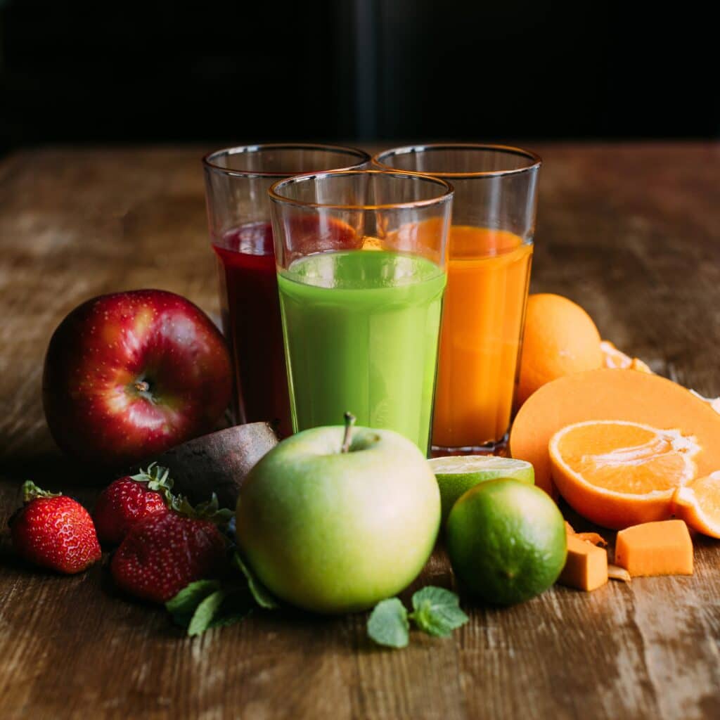 fruit juices on a wood table with assorted fruit on the table