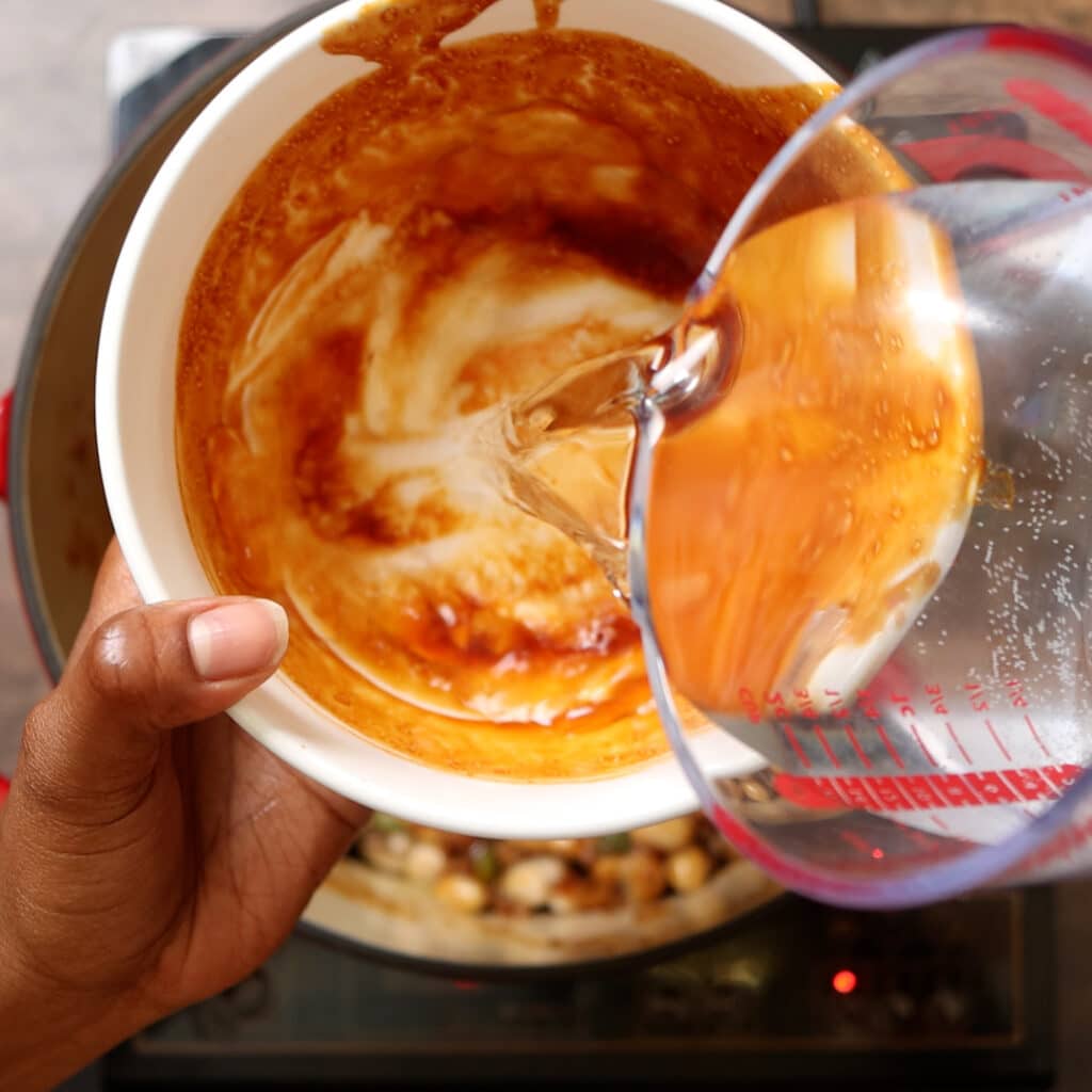 water being poured in a white bowl with left over sauce