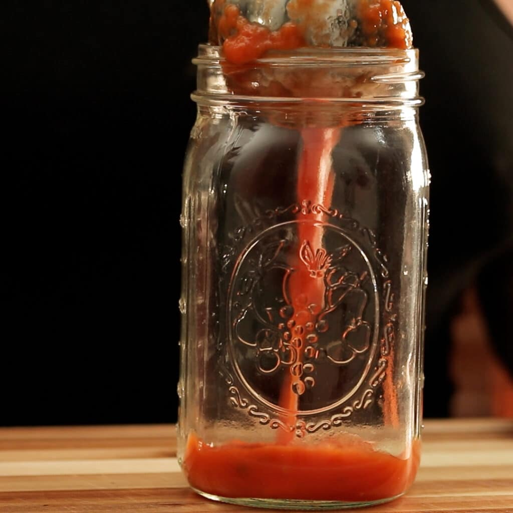 pouring tomato sauce in a jar