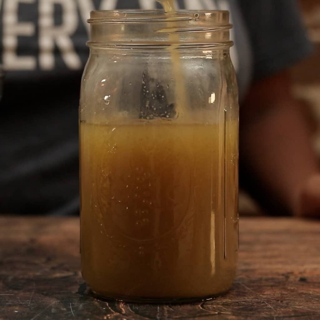 broth being poured in a mason jar