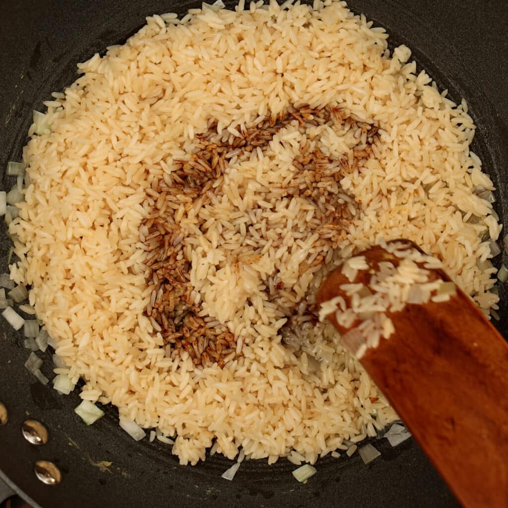 dark soy sauce poured on white rice in a wok