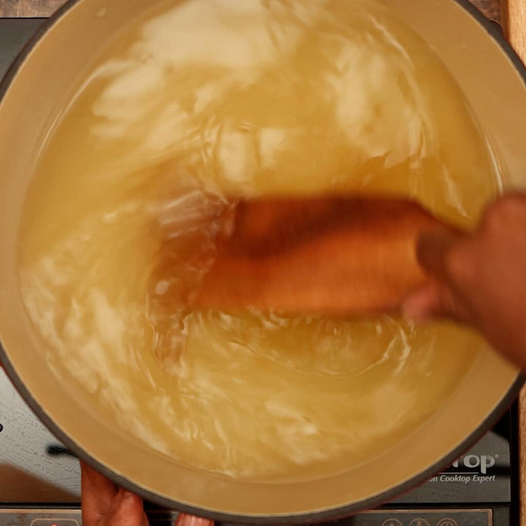 vegetable based broth being stirred into water inside a pot