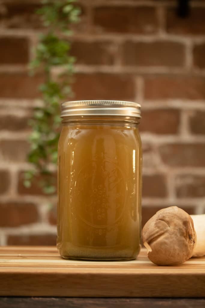 chicken broth in a jar next to a King Oyster Mushroom