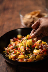 mango salsa being dipped with a chip