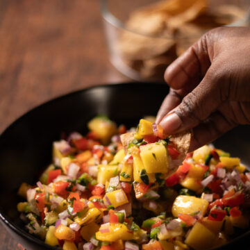 mango salsa being dipped with a chip