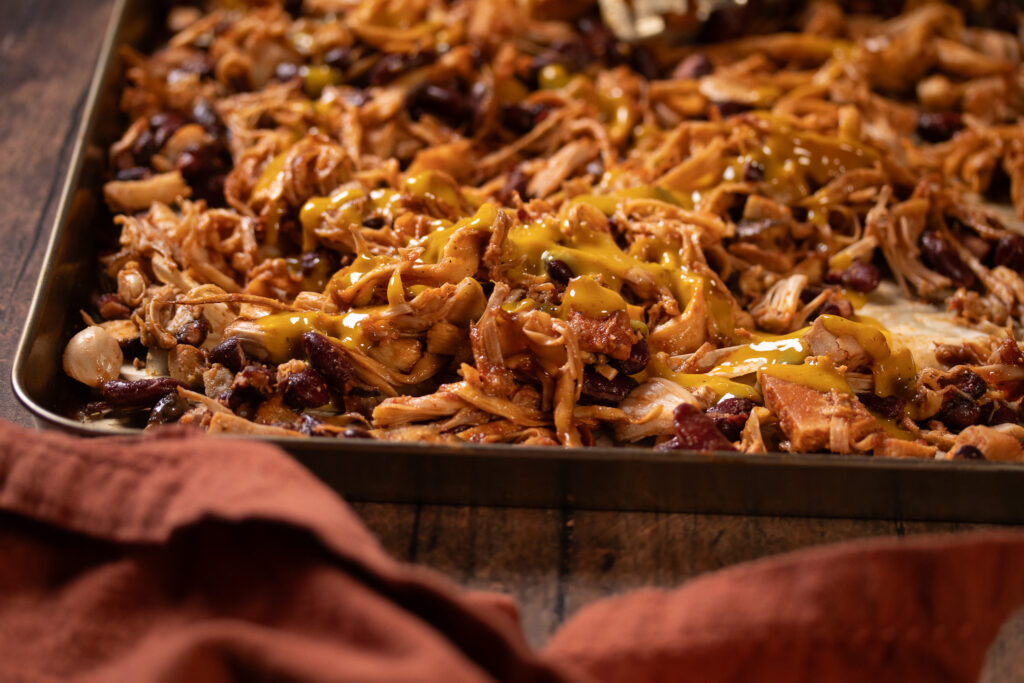 mustard BBQ sauce on vegan pulled pork on a sheet pan
