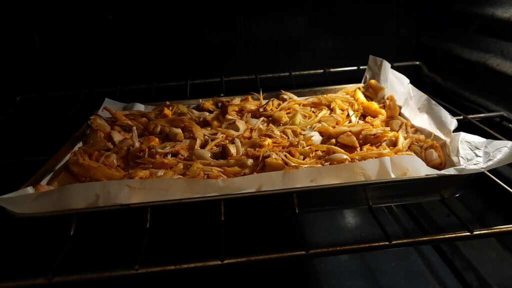 oyster mushrooms and jackfruit on a baking sheet placed in the oven